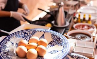 Närbild förberedda ägg gör omeletter till frukost med suddiga kock matlagning i ryggen. foto