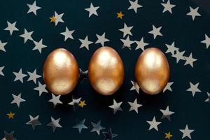 gyllene ägg på mörk bakgrund med lysa ljus stjärnor. ovanifrån koncept med brons ägg i platt låg stil. idé för hälsningar och påsk foto