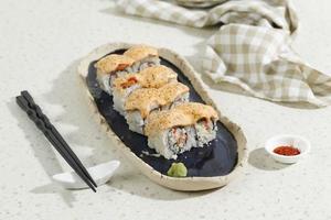 japansk mat lax mentai sushi rulle med krabba pinne på lång blå oval tallrik. foto