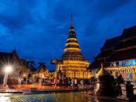 gyllene pagoden vid wat phra att hariphunchai under hundratusen lyktafestival i lamphun buddhistisk dyrkan med mörkblå himmel, lamphun, thailand. foto