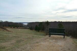 bänk eller stol på gräskulle med utsikt över skogen och floden Potomac foto