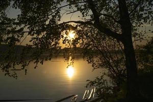 solnedgång på floden genom träden foto