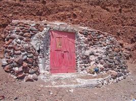 dörr med stenar i röd strand Santorini Grekland foto