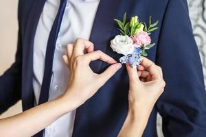 bruden korrigerar brudgummen boutonniere på deras bröllop foto