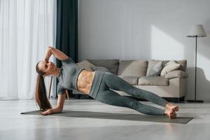 stretchövningar. ung kvinna med smal kroppstyp och i yogakläder är hemma foto