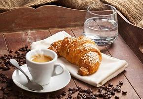 espresso med croissant och ett glas vatten. foto