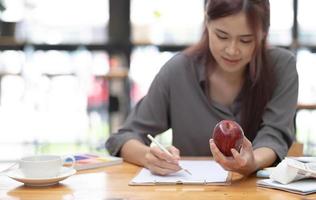 ung asiatisk kvinnlig grafisk designer skissar äpple på sitt projekt med modern kreativ arbetsplats foto