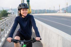 ung asiatisk cyklist kvinna tränar genom att cykla. cykling är fantastiskt för dem som letar efter en annan form av konditionsträning eller aerob träning än löpning. foto