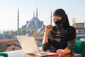 traditionellt klädd muslimsk kvinna som arbetar på datorn