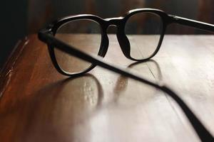 grunt fokus närbild skott av färglösa genomskinliga glasögon på ett träbord foto