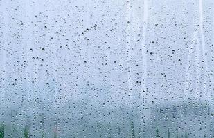 regndroppe på glasfönstret på dagtid i monsunsäsongen med suddig bakgrund. foto