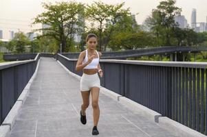 ung fitness kvinna i sportkläder joggar i stadsparken, hälsosam och livsstil. foto