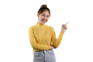 porträtt av en vacker asiatisk kvinna i en gul skjorta som står och pekar. porträttkoncept som används för reklam och skyltar, isolerad över den tomma bakgrunden, kopieringsutrymme. foto