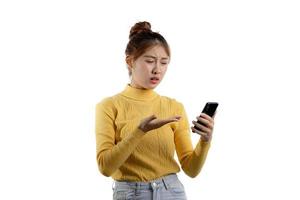 porträtt av en vacker asiatisk kvinna i en gul skjorta som spelar på en smartphone. porträttkoncept som används för reklam och skyltar, isolerad över den tomma bakgrunden, kopieringsutrymme. foto