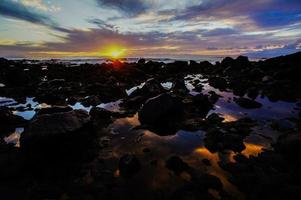 tropisk solnedgång över stenar foto
