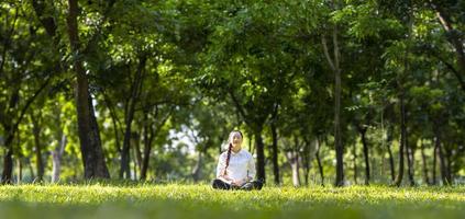 kvinna som avkopplande övar meditation i skogen för att uppnå lycka från inre frid visdom med strålen av solljus för ett hälsosamt sinne och själ koncept foto