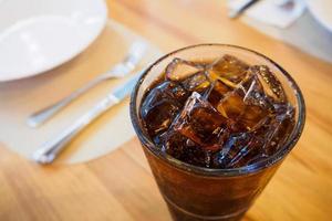 colaglas läsk med is på träbord i restaurangbakgrund foto