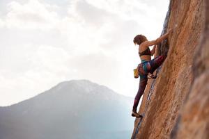 en kvinna klättrar på en sten foto