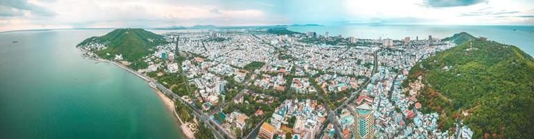 vung tau stadens flygfoto med vacker solnedgång och så många båtar. panoramautsikt över kustnära vung tau från ovan, med vågor, kustlinje, gator, kokospalmer och tao phung-berget i vietnam. foto