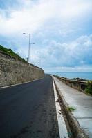 perfekt roadtripdestination under solnedgången på en ö i vietnam. panoramautsikt över kusten lång hai med vågor, kustlinje, klar himmel och väg, blått hav och berg. foto