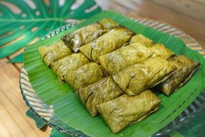 khao tom mad eller ångad mungböna med klibbigt ris är den lokala och traditionella thailändska desserten. den är insvept av bananblad. foto