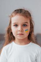 porträtt av liten flicka med ukrainska flaggan smink i ansiktet foto