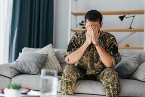 med tillbakablickar. posttraumatisk stressyndrom. soldat i uniform sitter inomhus foto