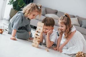 spelar trätornspel. grupp barn är tillsammans hemma på dagtid foto