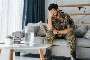 posttraumatisk stressyndrom. soldat i uniform sitter inomhus foto