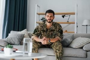 på soffan. posttraumatisk stressyndrom. soldat i uniform sitter inomhus foto