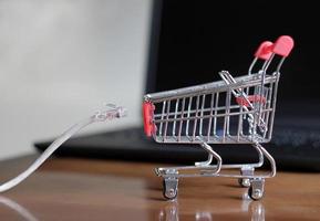 framgångsrik online-affär - nätverkskabel och shoppingvagn framför en bärbar dator foto