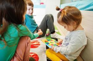 lycklig familj som har roligt tillsammans, fyra barn spelar twister-spel hemma. foto