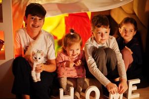 lekande barn med kattunge i tält på natten hemma. hygge humör. foto