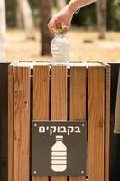 ramat gan, israel, 21 maj 2022. flickans hand kastar använd plastflaska till soptunnan för flaskorna foto
