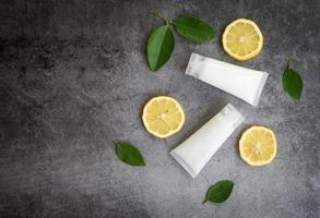 lotionflaska naturlig för ansikts- och kroppsskönhetsmedel och organisk minimalistisk livsstil med citronlimeskiva och gröna blad örtformuleringar på svart bakgrund foto