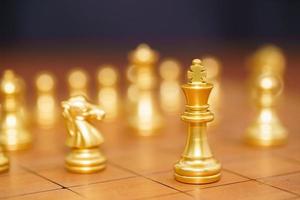 guld kung schackpjäser stå på trä schackbräde foto