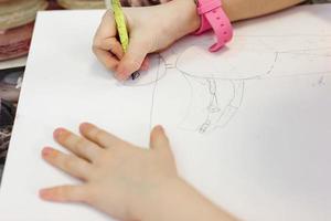beskuren bild av liten flicka ritar på ett papper med en penna. foto