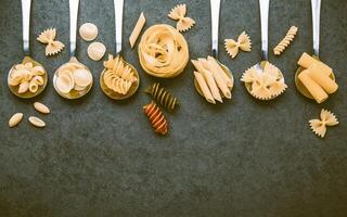 italiensk matkoncept och menydesign. olika sorters pasta farfalle, pasta a riso, orecchiette pugliesi, gnocco sardo och farfalle i metallskedar setup på sten bakgrund med platt låg. foto