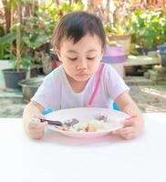 asiatisk liten flicka äter smaklös mat till lunch, aptitlöshet. foto