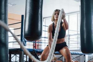 attraktiv mogen tjej. blond sport kvinna har träning med rep i gymmet. stark hona foto