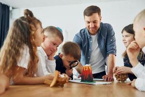 tittar på modellen av vulkan. grupp barn elever i klassen i skolan med lärare foto