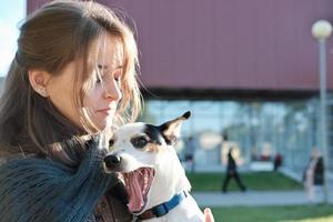 ung kvinna med jack russel terrier hund vit det gäspar. glad hund med ägare utomhus. husdjursvän, kärlek och gemenskap. foto