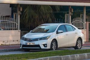 manavgat Turkiet 5 mars 2022 vit Toyota Corolla är parkerad på gatan en varm dag mot bakgrund av en byggnad, träd foto