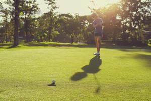 golfspelare sätta golfboll i hål foto