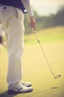 golfspelare på puttinggreen slår bollen i en hole.vintage färg foto