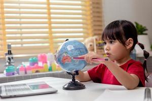 Asiatisk liten flicka lär sig världsmodellen, konceptet att rädda världen och lära sig genom lekaktivitet för barnutbildning hemma. foto