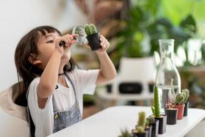 kid röra försiktigt nya stjälken av kaktusen han odlar med omsorg, en hand håller förstoringsglaset. naturutbildning, montessori och observationsfärdigheter koncept. foto