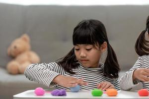 den lilla flickan lär sig att använda färgglad lekdeg i ett väl upplyst rum foto
