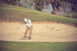 golfare slår bollen i sanden. hastighet och styrka.vintagefärg foto