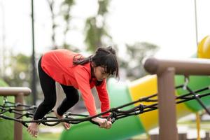 sommar, barndom, fritid och människor koncept - glad liten flicka på barnens lekplats klättringsram foto